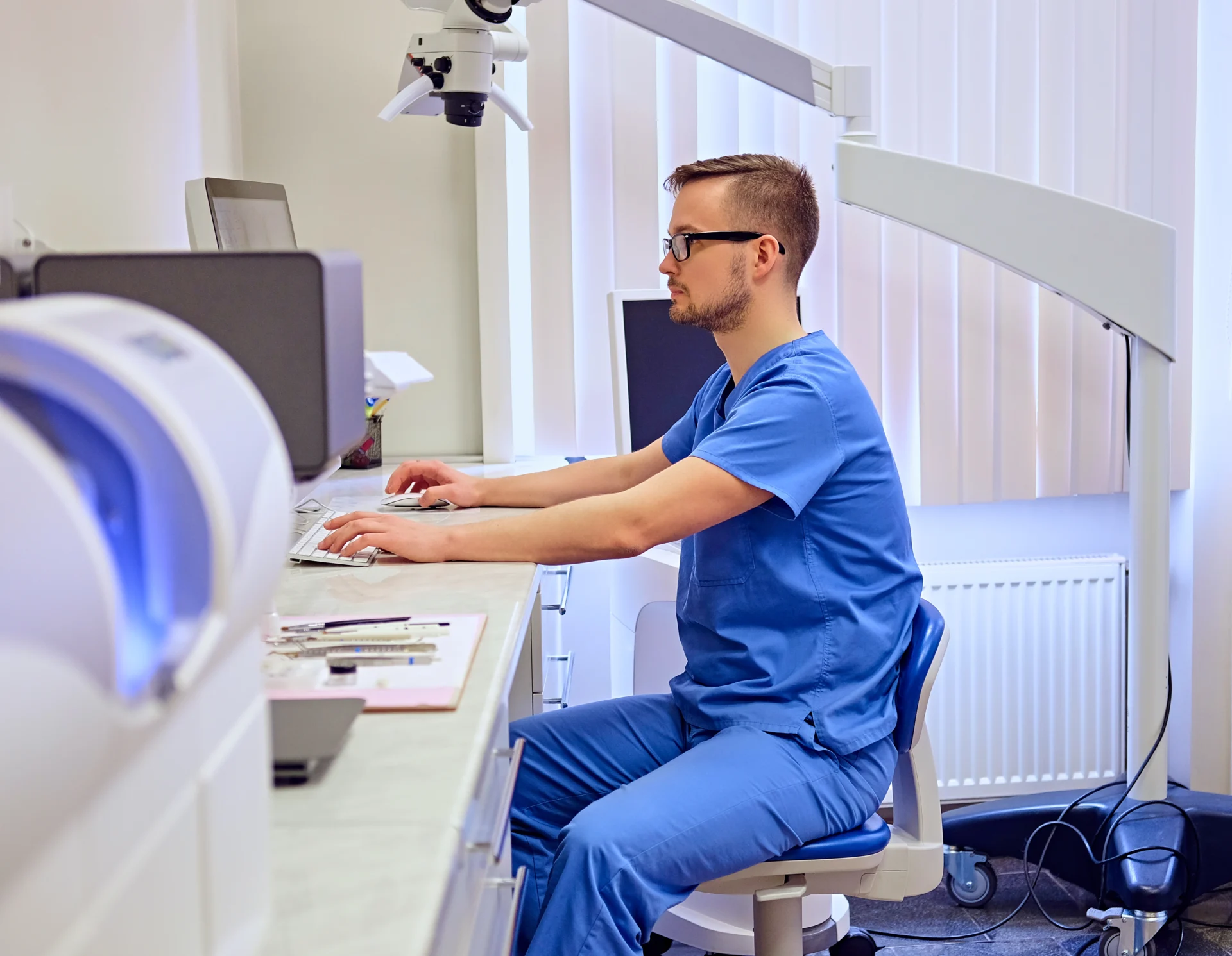 Handsome male dentis using computer room with medical equipment background